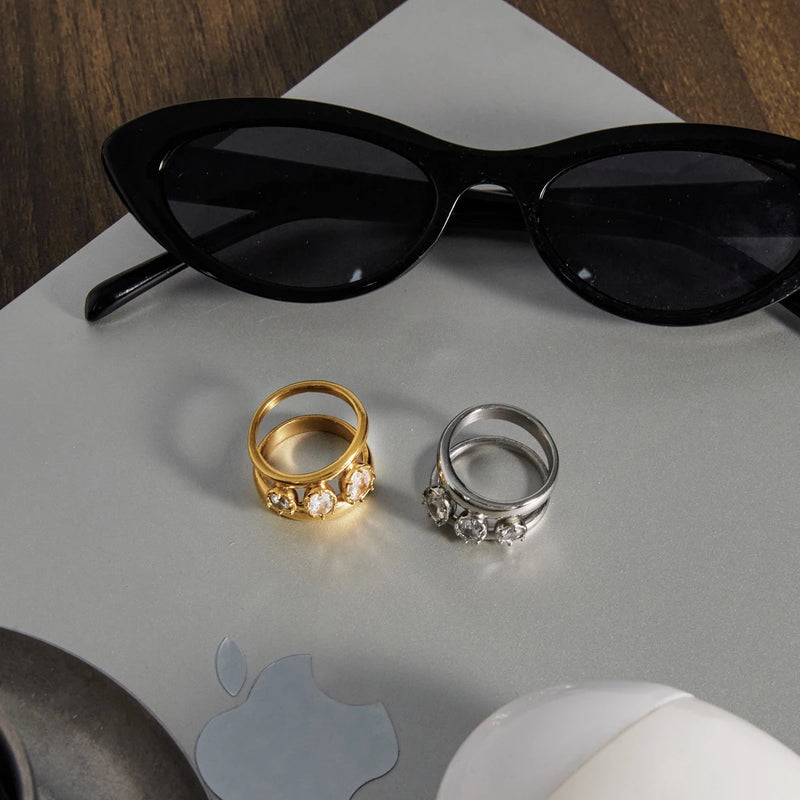 Antoinette Three-Stone Double Band Ring, both colourways beside a pair of sunglasses