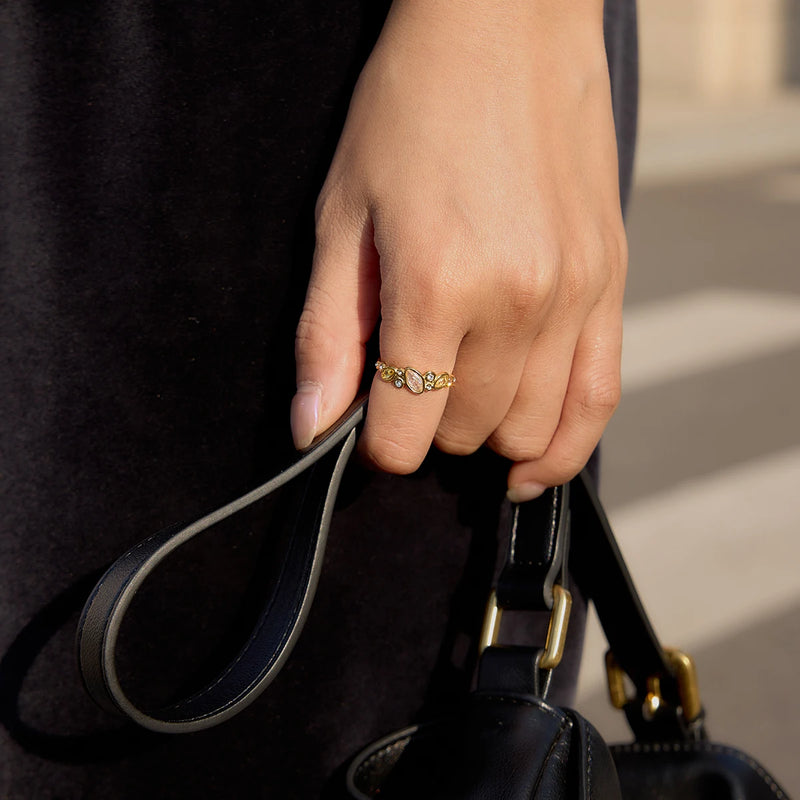 Open crystal ring worn on a hand holding a black bag strap
