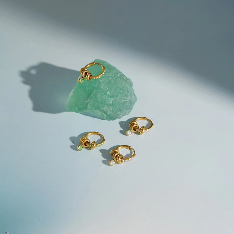 Two small crystal-set hoops beside a rough green stone