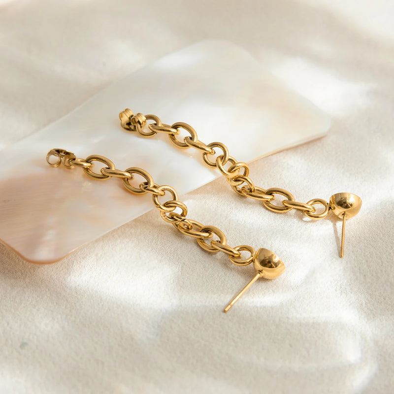 Two chain drop earrings laid out on cream fabric