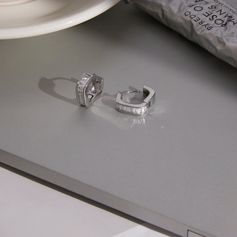 Pair of baguette crystal huggie hoops on a grey surface