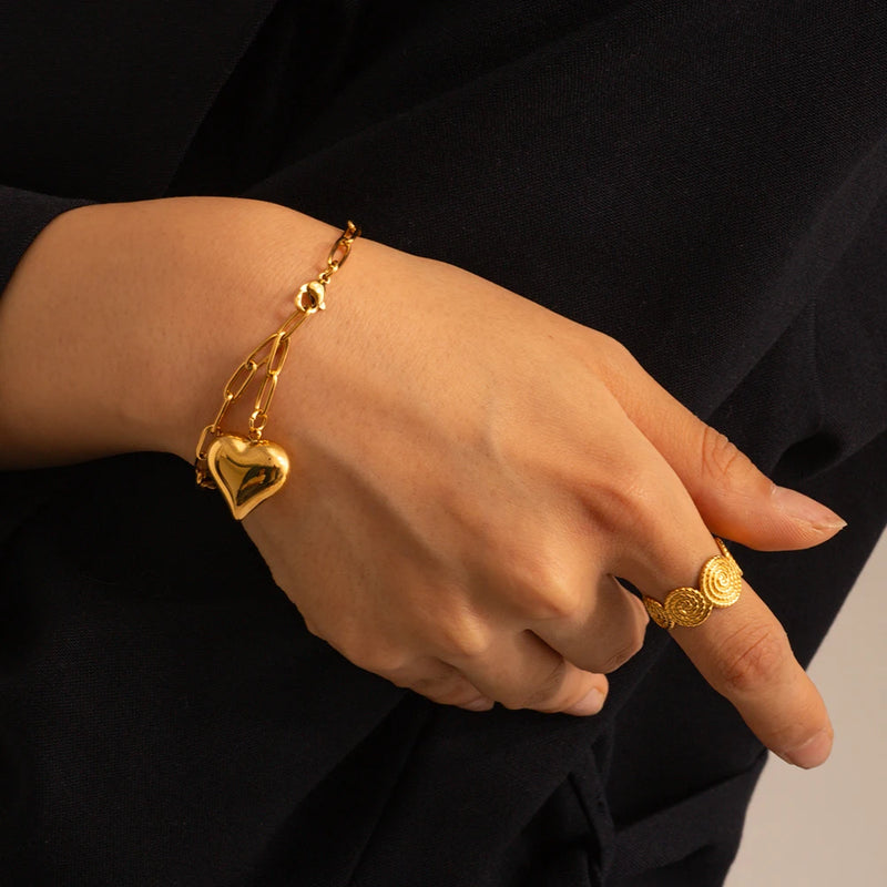 Paperclip chain bracelet with a puffed heart charm worn on a wrist