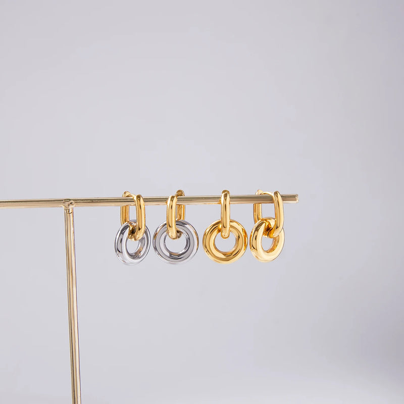 Maud Interlocking Ring Hoop Earrings hung on a display bar