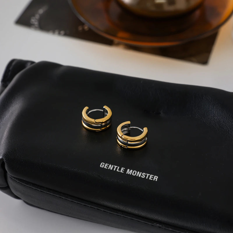 Two-tone huggie hoops resting on a black bag