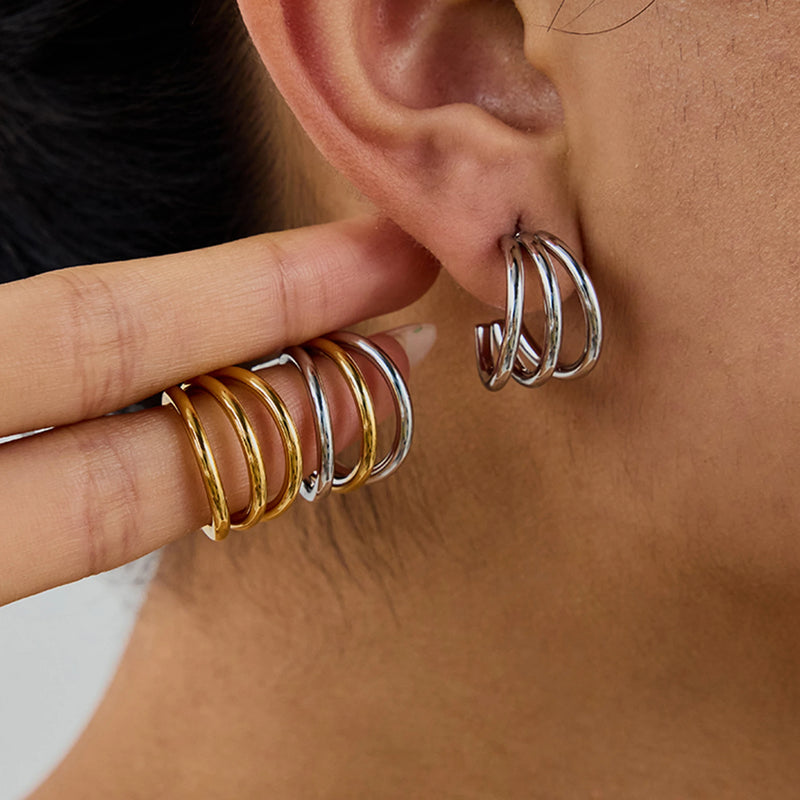 Henriette Triple-Band Hoop Earrings held beside the ear in gold-tone and silver-tone