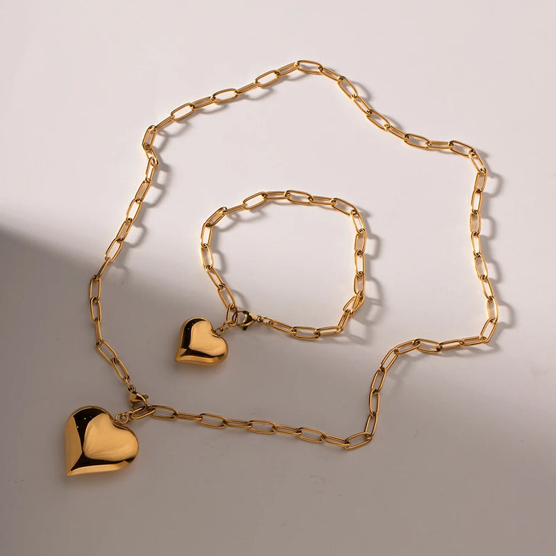 Matching heart necklace and bracelet laid out on a pale surface