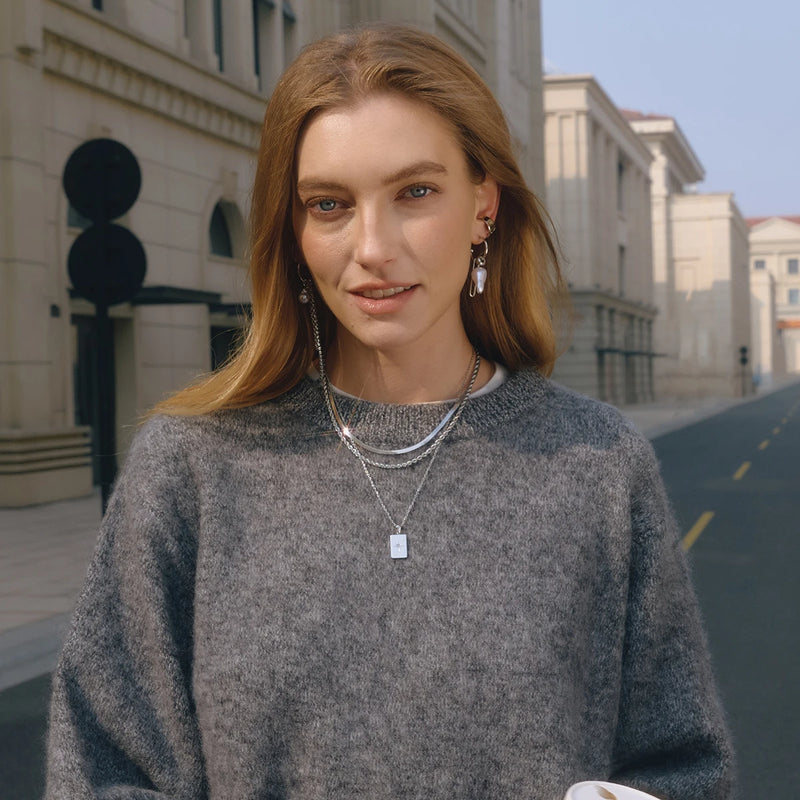 Model outdoors wearing the layered silver-tone star tag necklace