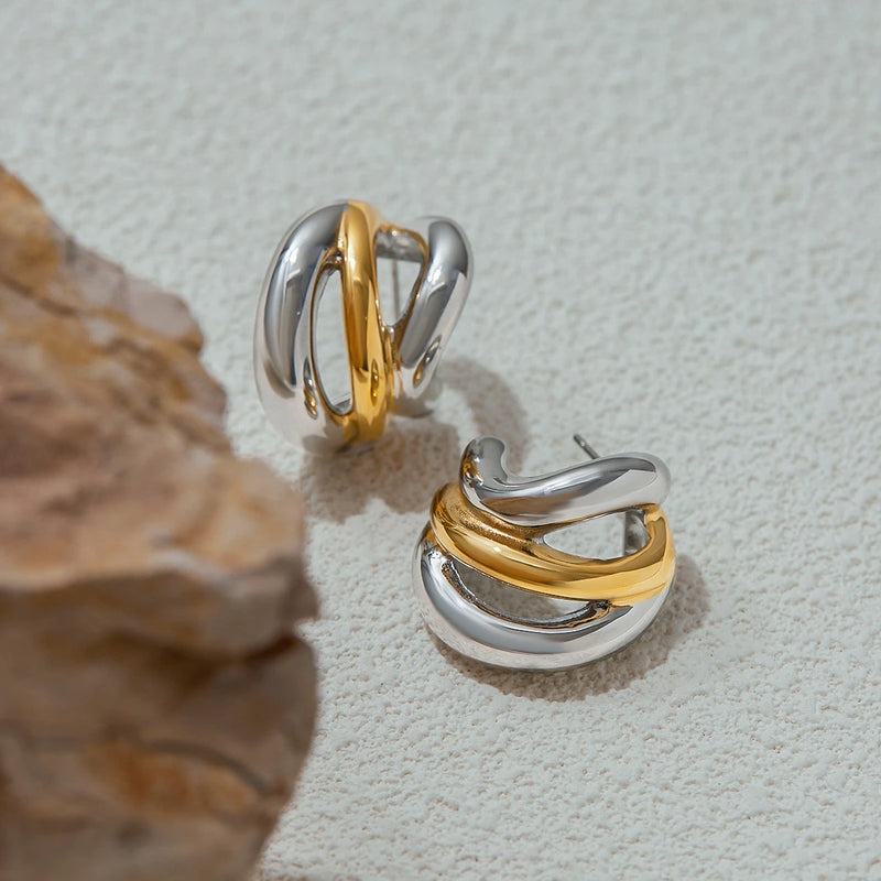 Two-tone crossover hoops on a pale surface with dried wood