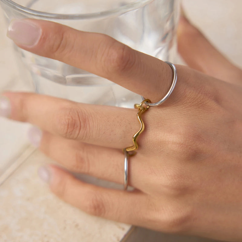 Gold-tone wave ring and a plain band worn on two fingers