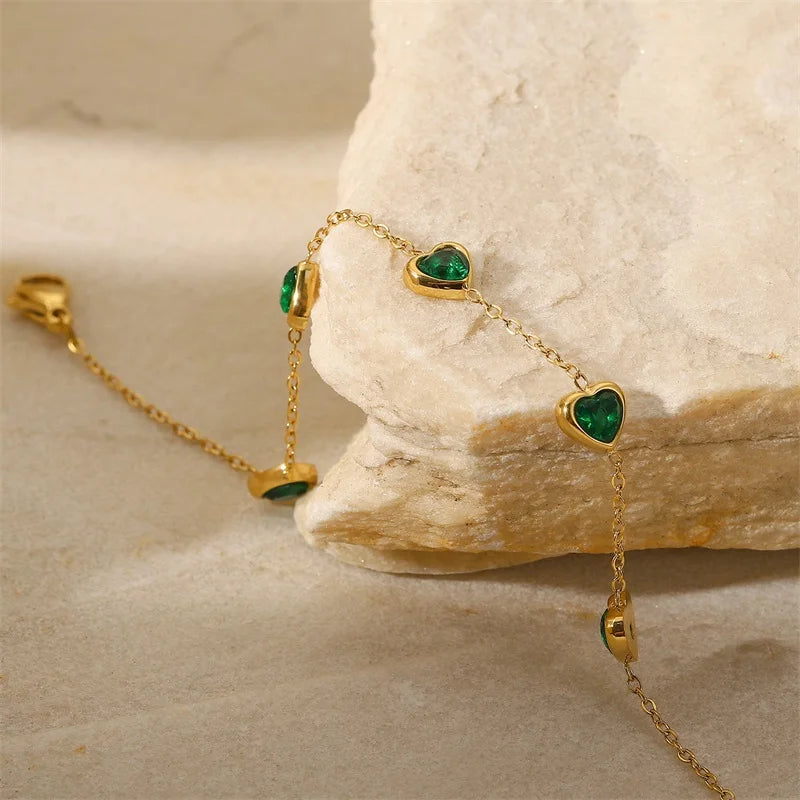 Green heart station bracelet resting against pale stone