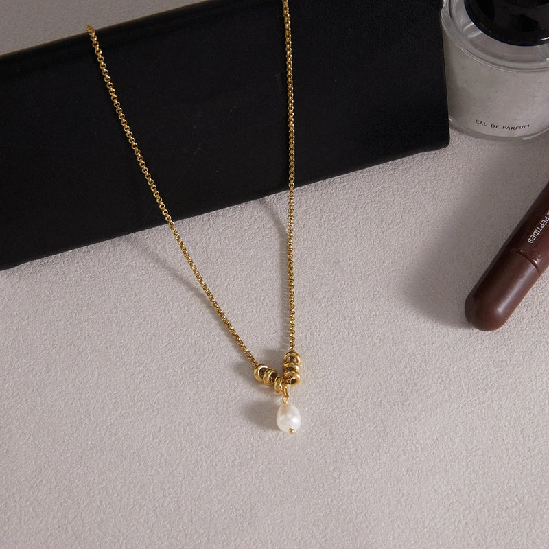 Necklace laid on a pale surface beside a black card
