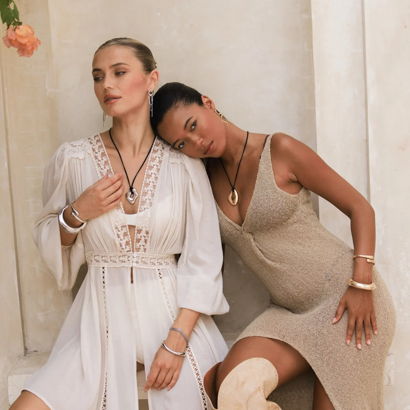 Two models wearing pebble pendant cord necklaces