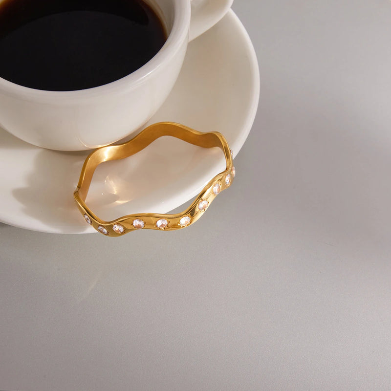 Wavy crystal bangle resting against a cup and saucer
