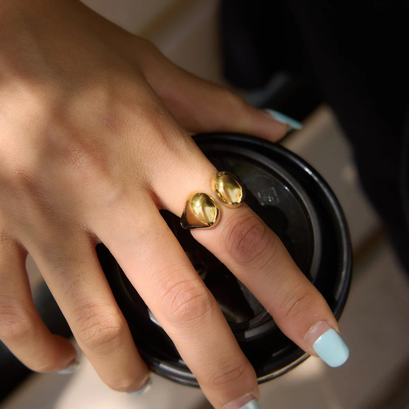 Gold-tone double-dome ring worn on a hand holding a cup lid