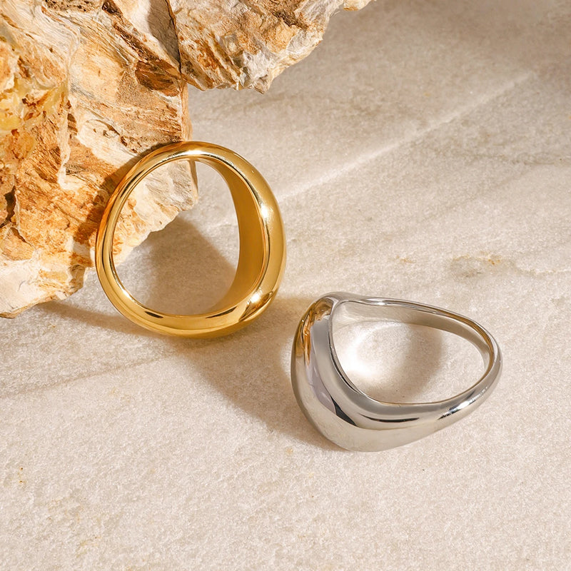 Ludivine Sculptural Wave Ring, gold-tone and silver-tone beside a rock