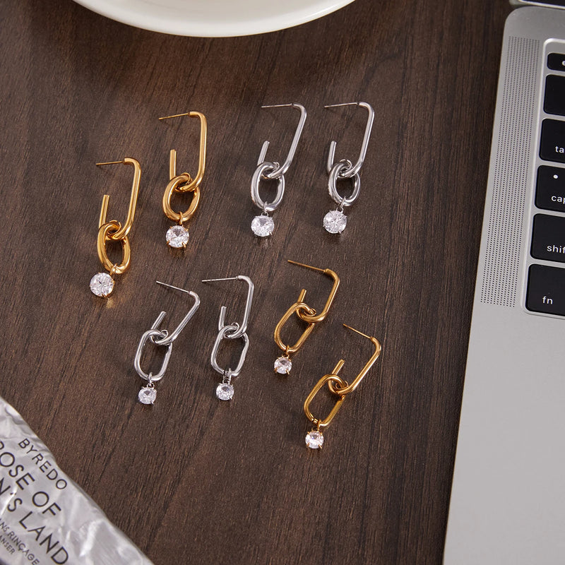 Several pairs of link drop earrings on a dark wooden surface