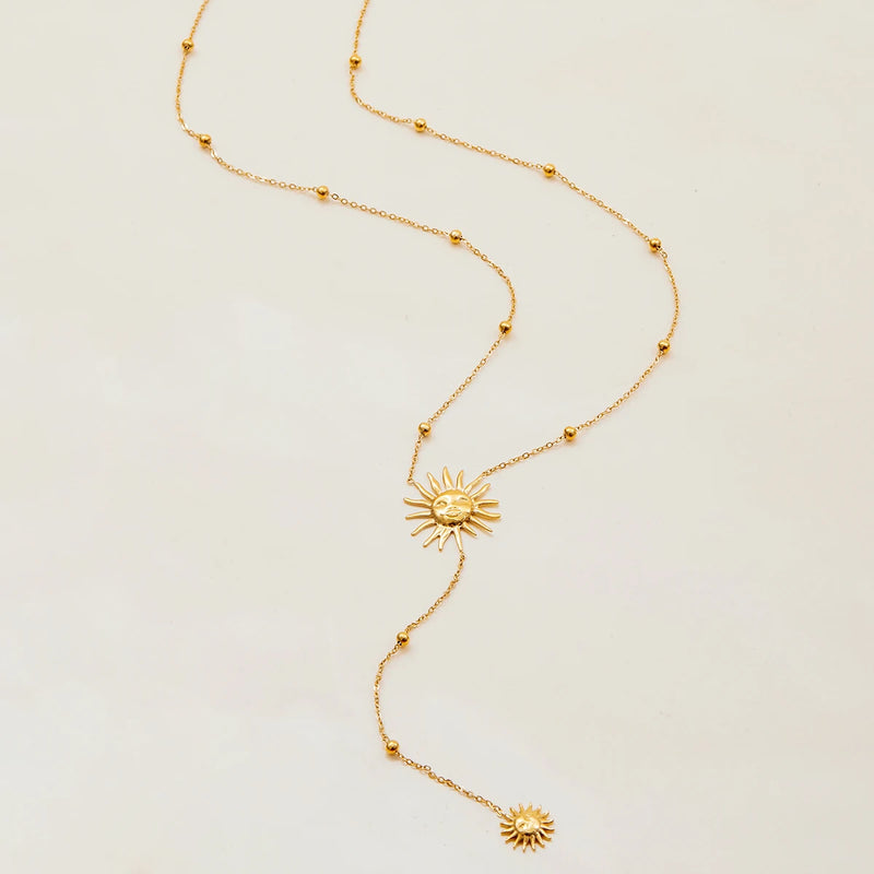 Sun lariat necklace with beaded chain on a cream surface