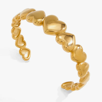 Open cuff formed from a row of puffed gold-tone hearts