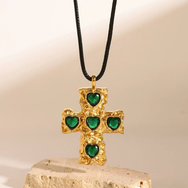 Green heart stone cross pendant propped on pale stone