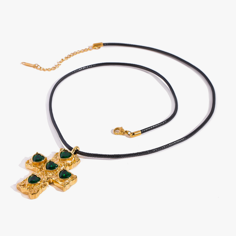 Gold-tone cross set with green heart stones on a black cord