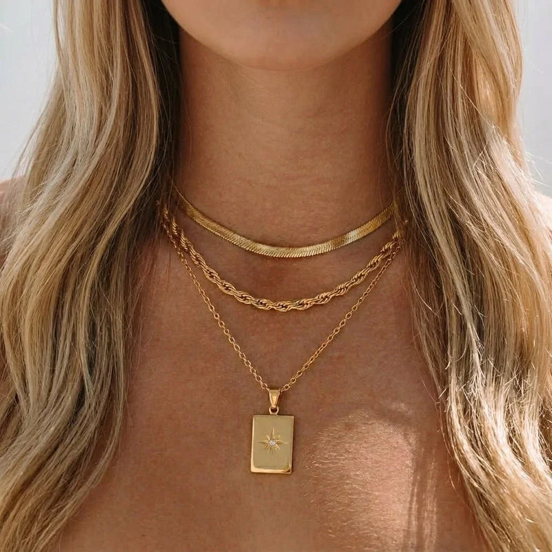 Gold-tone layered chains with a rectangular star tag at the neck
