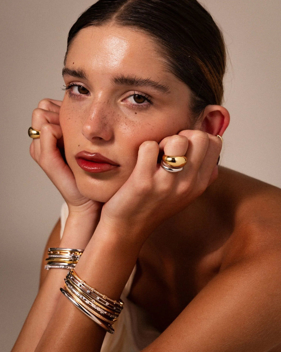 Domed gold rings and a mixed-metal bangle stack in a studio portrait