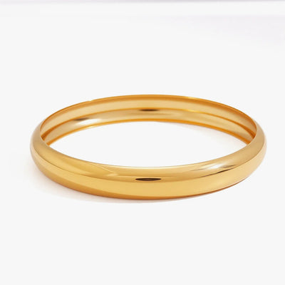 Smooth rounded gold-tone bangle on a white background