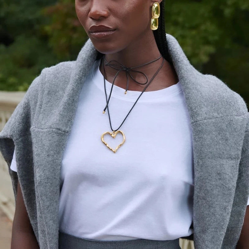 Open heart necklace worn with a white tee and grey knit