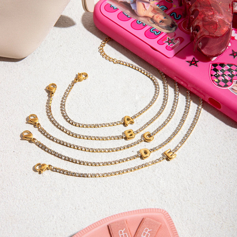 Pauline Initial Crystal Tennis Bracelet, several letters laid on a pale surface